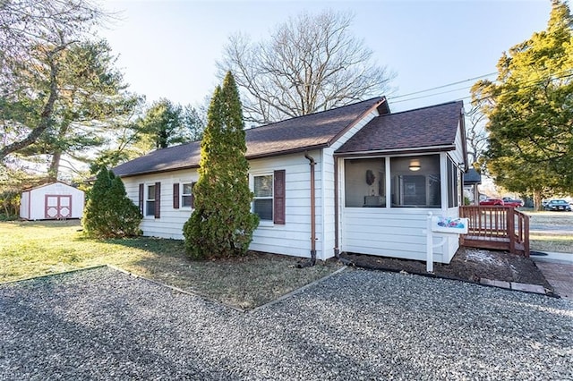 single story home featuring a front lawn, a storage unit, and a sunroom