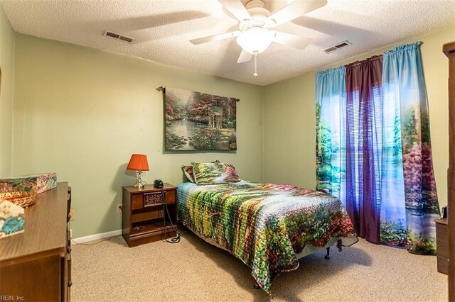 carpeted bedroom featuring ceiling fan and a textured ceiling