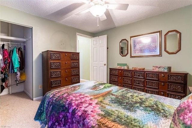 bedroom with a textured ceiling, a closet, ceiling fan, and light colored carpet