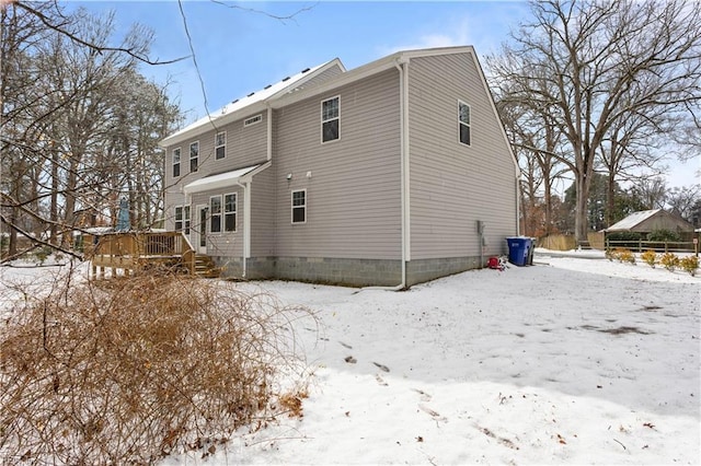 snow covered rear of property with a deck