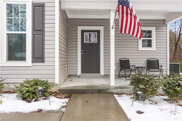 snow covered property entrance featuring covered porch