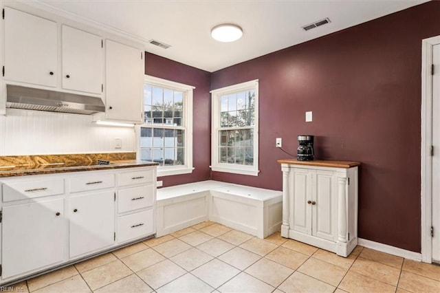 kitchen featuring black electric stovetop, light tile patterned floors, and white cabinets