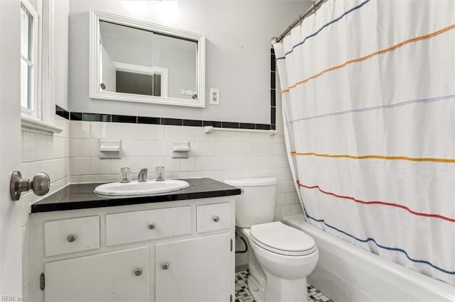 full bathroom featuring toilet, vanity, tile walls, and shower / bathtub combination with curtain