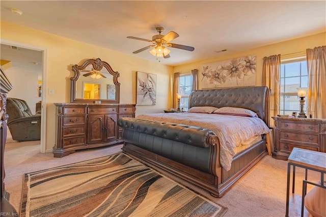 bedroom featuring multiple windows, light carpet, and ceiling fan