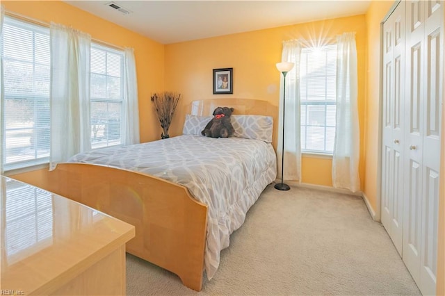 carpeted bedroom with multiple windows and a closet