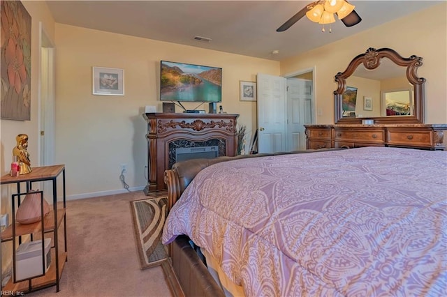 carpeted bedroom with ceiling fan and a high end fireplace