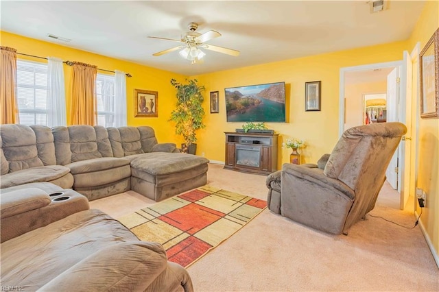 carpeted living room with ceiling fan and a fireplace