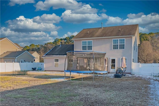 rear view of house with a lawn and a trampoline