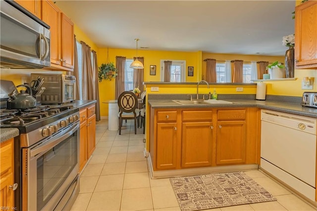 kitchen featuring kitchen peninsula, sink, light tile patterned flooring, and appliances with stainless steel finishes