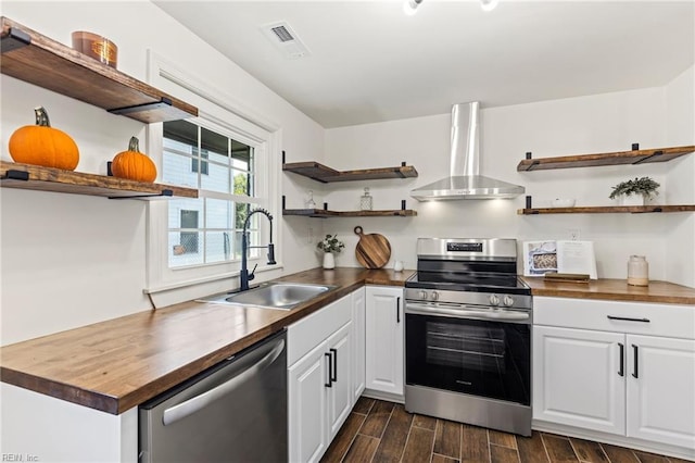 kitchen with wooden counters, stainless steel appliances, wall chimney exhaust hood, and sink