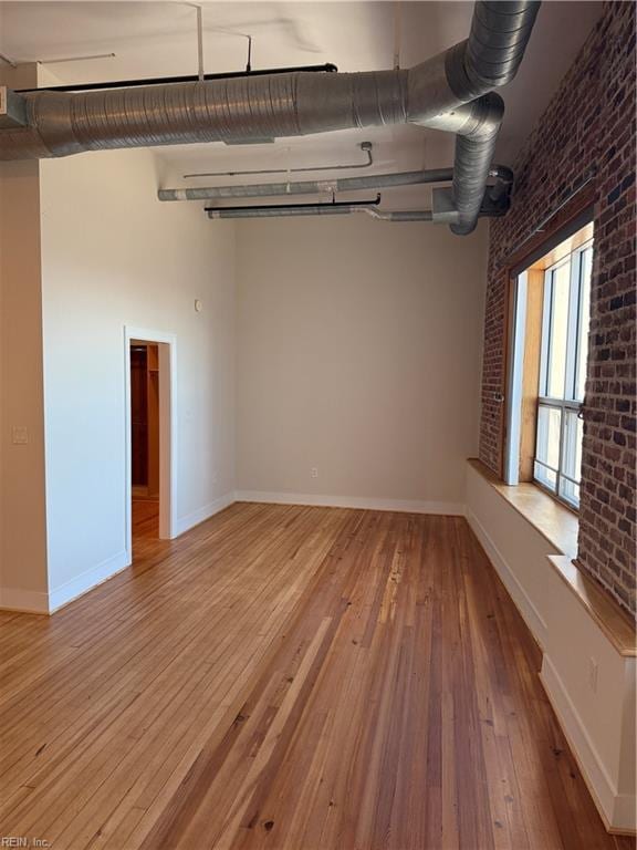 spare room with light hardwood / wood-style flooring and brick wall