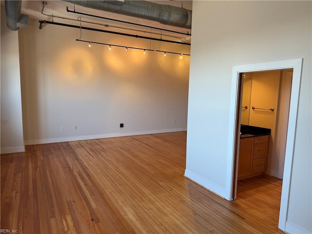 spare room featuring rail lighting and light hardwood / wood-style floors