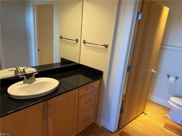 bathroom featuring toilet, vanity, and hardwood / wood-style flooring