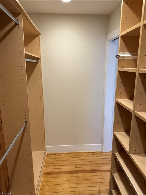 walk in closet with light hardwood / wood-style flooring