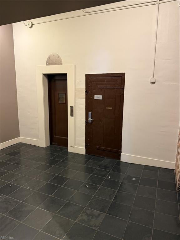 foyer entrance featuring dark tile patterned flooring and elevator