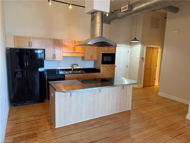 kitchen featuring sink, a high ceiling, island range hood, a kitchen island, and black appliances