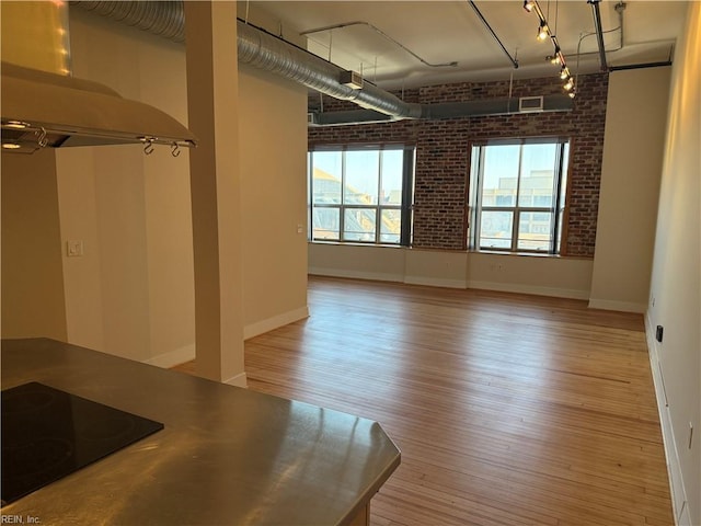 unfurnished room with light hardwood / wood-style flooring and brick wall