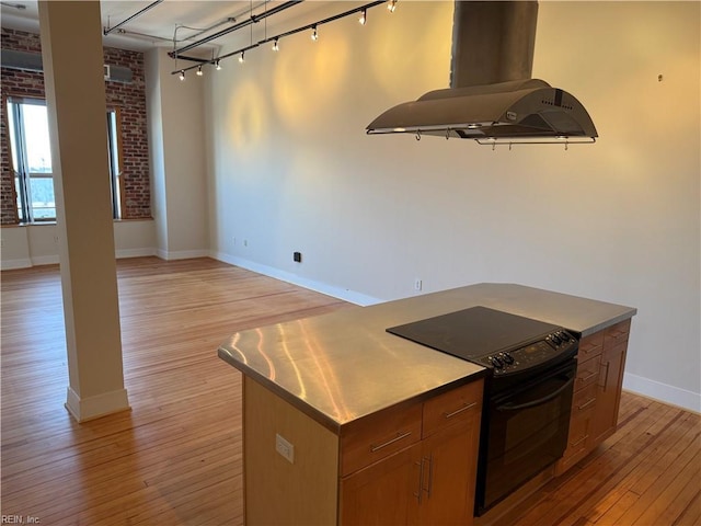 kitchen with black / electric stove, island range hood, a center island, and light wood-type flooring