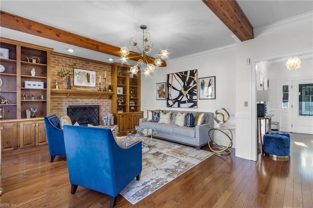 living room with an inviting chandelier, a fireplace, built in features, ornamental molding, and wood-type flooring