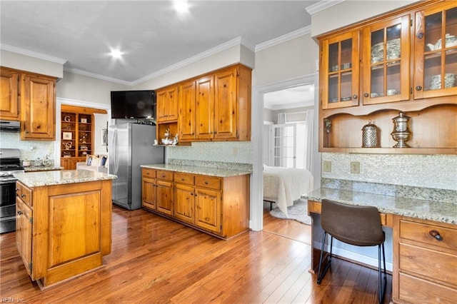 kitchen with appliances with stainless steel finishes, ornamental molding, light stone counters, and decorative backsplash