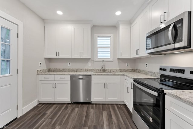 kitchen with white cabinetry, sink, light stone countertops, dark hardwood / wood-style flooring, and appliances with stainless steel finishes