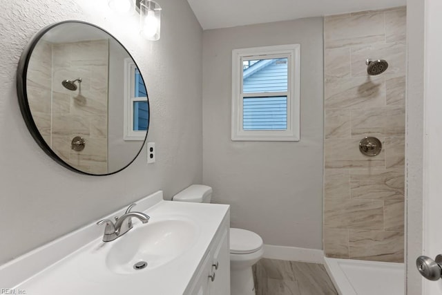 bathroom with a tile shower, vanity, and toilet