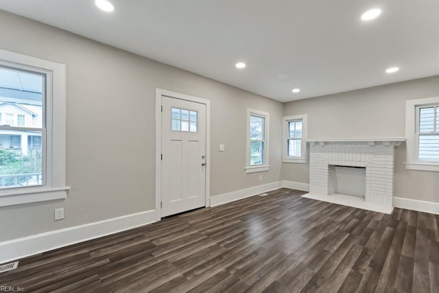 interior space featuring dark hardwood / wood-style flooring and a brick fireplace