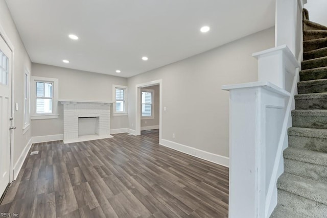 unfurnished living room featuring a fireplace and dark wood-type flooring