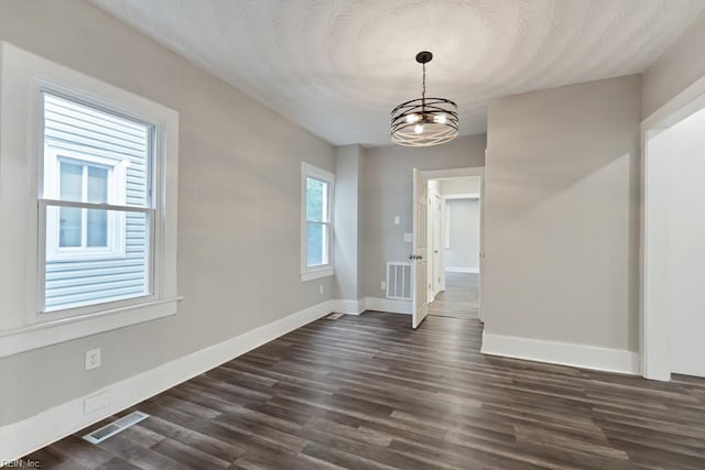 unfurnished dining area with dark wood-type flooring and a notable chandelier