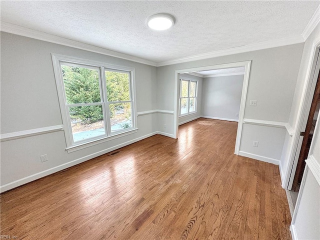 spare room featuring ornamental molding, a textured ceiling, and light hardwood / wood-style flooring