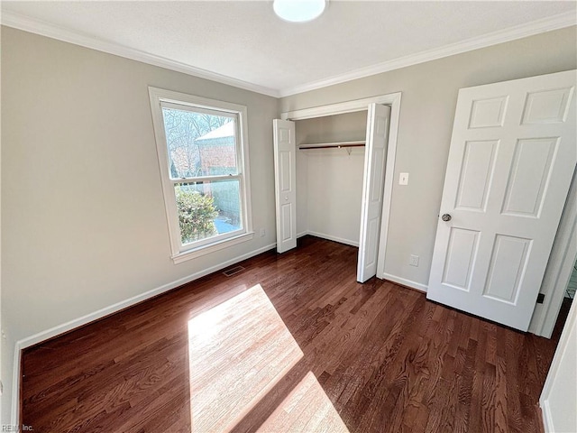 unfurnished bedroom with dark hardwood / wood-style floors, a closet, and crown molding