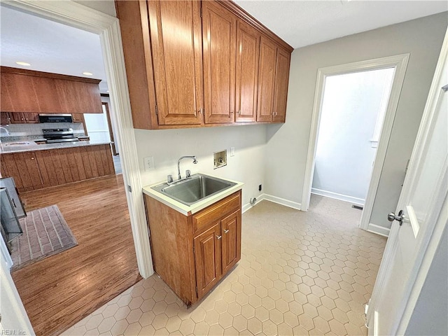 kitchen featuring electric range, sink, light tile patterned floors, and extractor fan