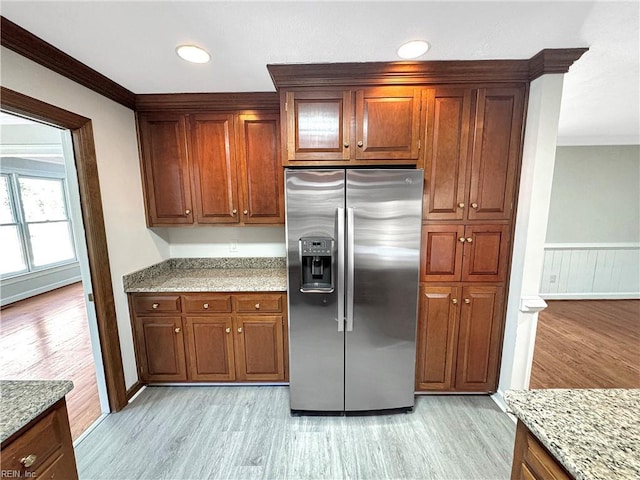 kitchen featuring light stone countertops, stainless steel fridge with ice dispenser, crown molding, and light wood-type flooring