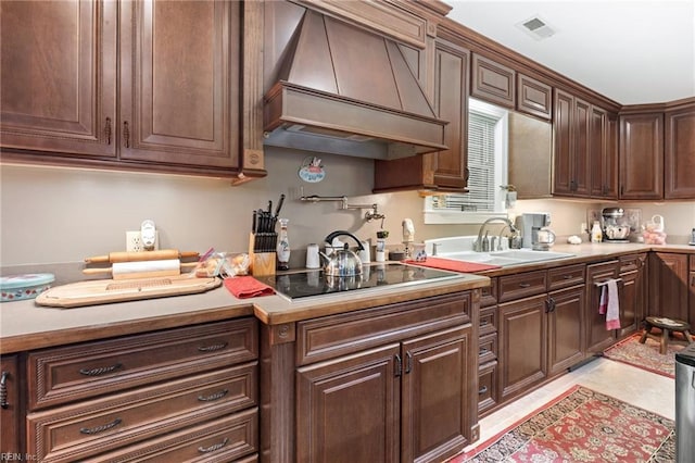 kitchen featuring premium range hood, dark brown cabinetry, black electric stovetop, and sink