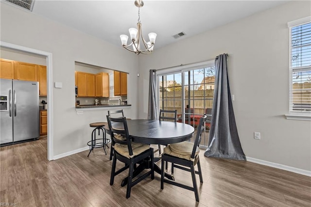 dining room with dark hardwood / wood-style flooring and an inviting chandelier