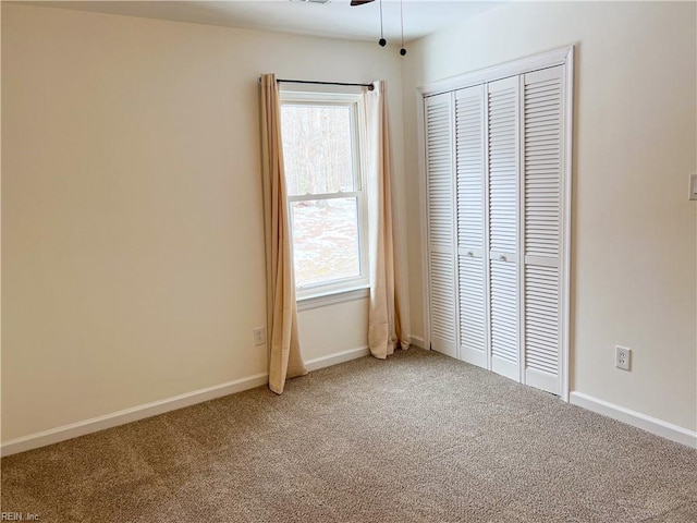 unfurnished bedroom featuring multiple windows, carpet floors, a closet, and ceiling fan