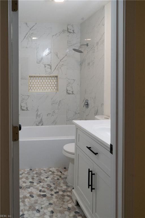 full bathroom with tiled shower / bath, vanity, and toilet