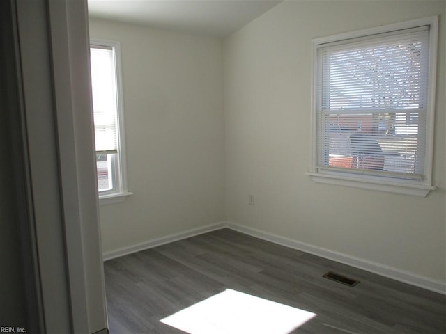 empty room with dark wood-type flooring and a wealth of natural light