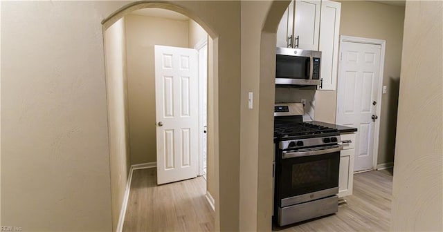 kitchen with light wood-type flooring, white cabinetry, and appliances with stainless steel finishes