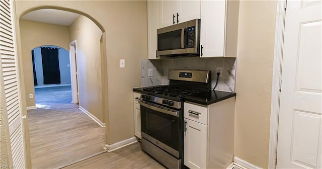 kitchen featuring white cabinets, backsplash, stainless steel appliances, and light hardwood / wood-style flooring