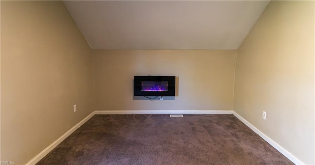 interior space featuring dark colored carpet and vaulted ceiling