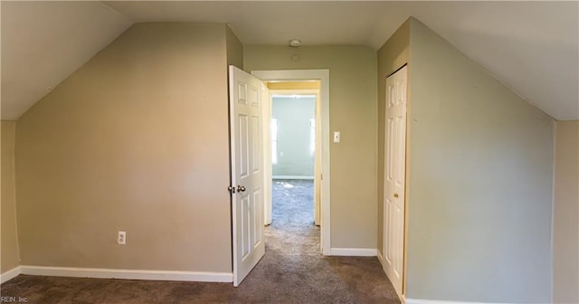 bonus room with dark carpet and vaulted ceiling