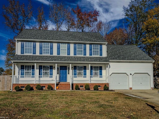 colonial house with covered porch, a garage, and a front lawn