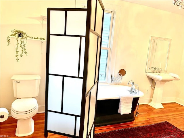 bathroom featuring toilet, a tub, and hardwood / wood-style floors