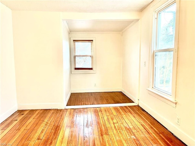 unfurnished room with plenty of natural light, crown molding, and light hardwood / wood-style floors