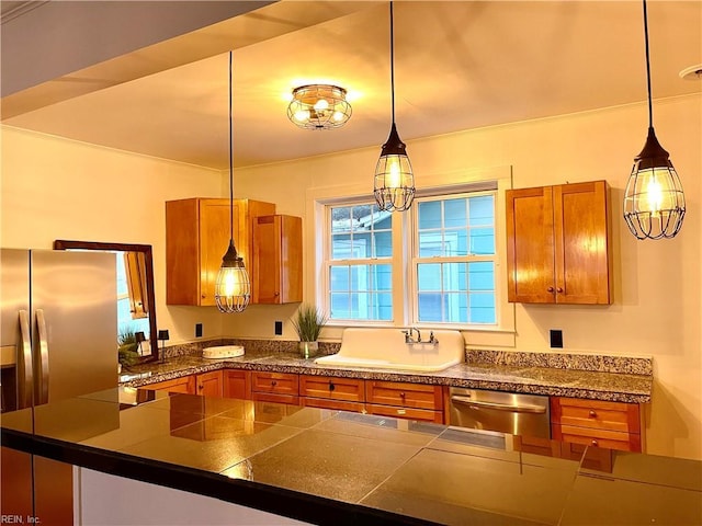 kitchen with appliances with stainless steel finishes, sink, and pendant lighting