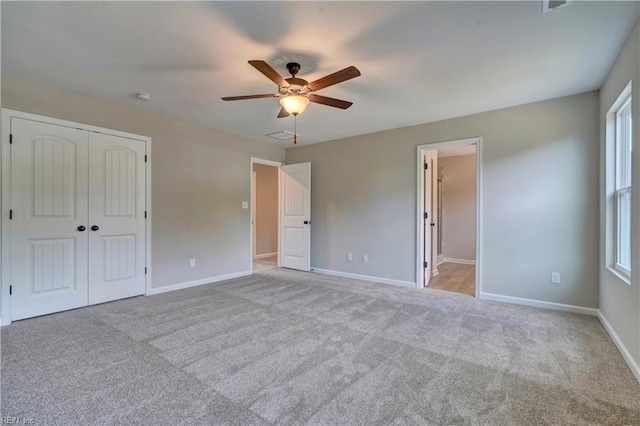 unfurnished bedroom with ensuite bath, ceiling fan, a closet, and light carpet