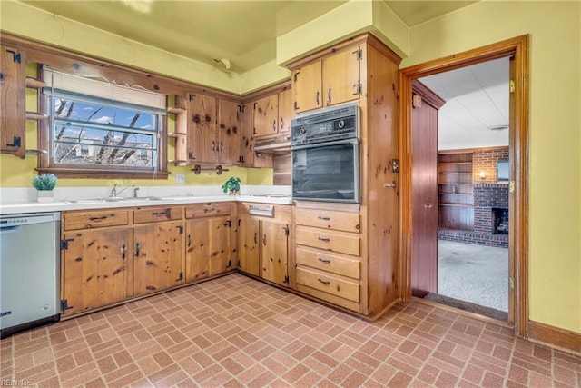 kitchen featuring stainless steel dishwasher, oven, a fireplace, and sink