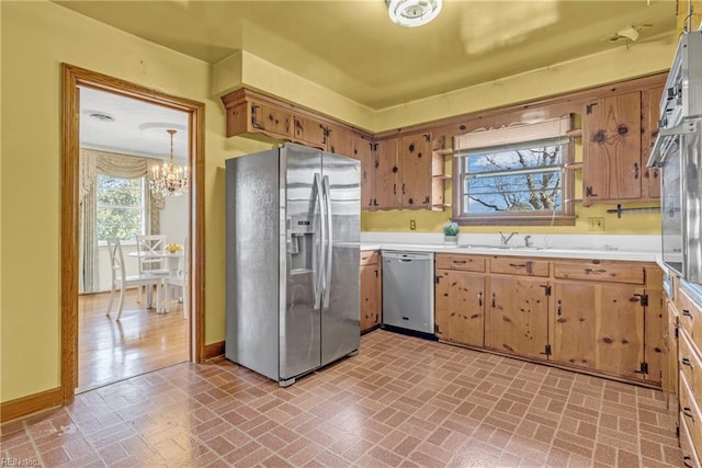 kitchen with sink, an inviting chandelier, hanging light fixtures, and appliances with stainless steel finishes