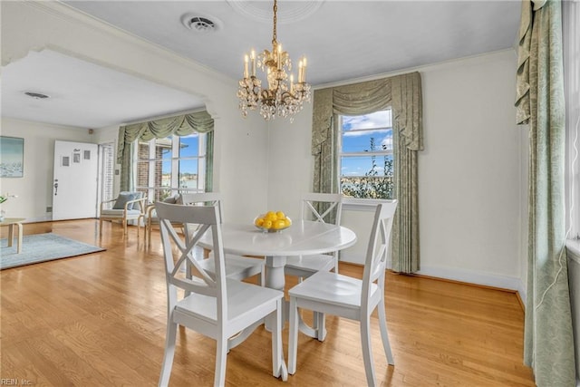 dining room featuring an inviting chandelier, light hardwood / wood-style floors, and crown molding